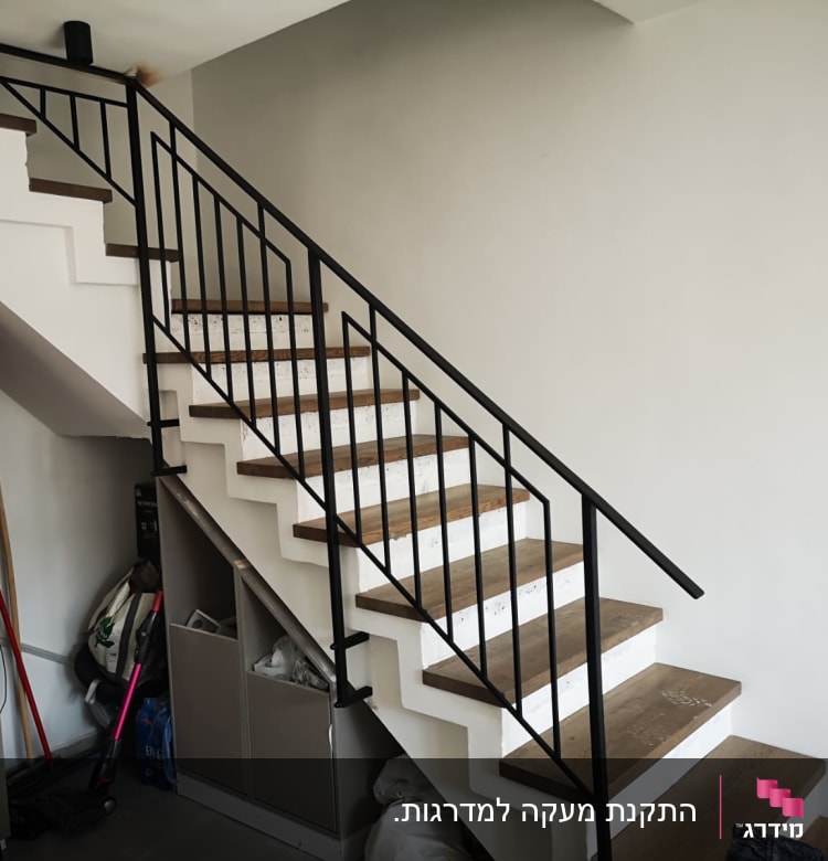 מעקה מתכת שחור על מדרגות עץ ולבן